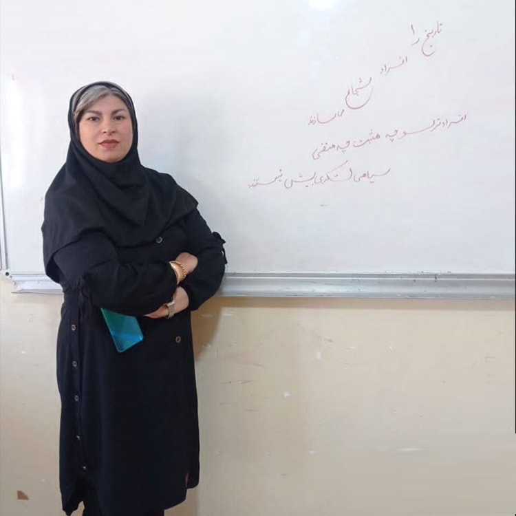 Kowkab Badaghi stands by a whiteboard, which reads, “Brave people are the ones who make history.”